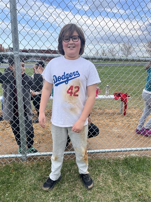 Student smiling in front of baseball field